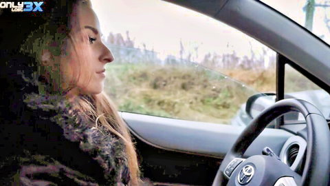 Shalina Devine in profile view driving car, long blonde hair, fur jacket