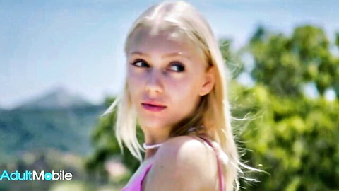 Sexy long-haired blonde babe with small tits in pink tube top posing seductively outdoors