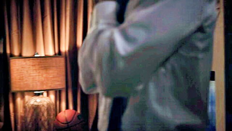Dimly lit bedroom corner with white shirted arms near lamp basketball and cue stick