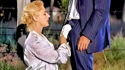 Vintage blonde in dress and gloves kneels touching suited man (Mamma 1998)