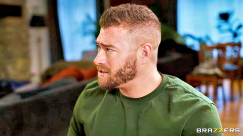 Muscular bearded man in green t-shirt grimacing sideways with open mouth in intense Brazzers scene