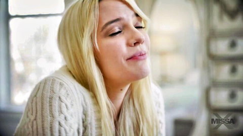 Blonde teen purses lips sensually in white sweater closeup tease