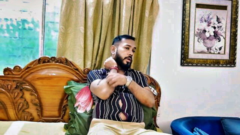 Bearded Indian mature man in striped shirt lounging on bed