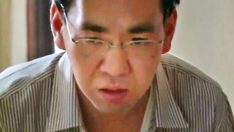 Close-up of Asian man with glasses in striped shirt looking serious
