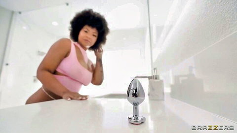 Curvy ebony babe with big tits in pink tank top eyes steel butt plug on bathroom counter