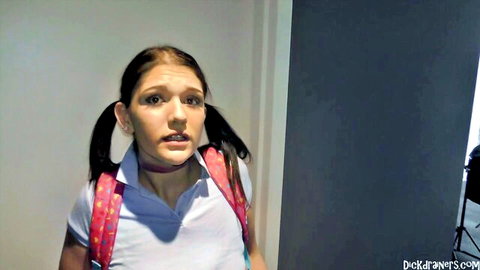 Shocked young brunette schoolgirl with pigtails in tight white uniform and backpack