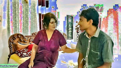 Indian MILF in deep purple V-neck dress touches young guy's arm intimately on ornate sofa