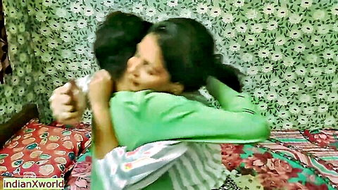 South Asian couple in passionate clothed hug in green bedroom