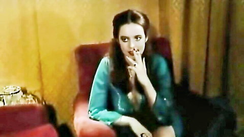Vintage brunette in teal blouse smoking seductively in classic adult scene