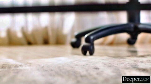 Blurry close-up of black office chair wheels on beige floor in adult video