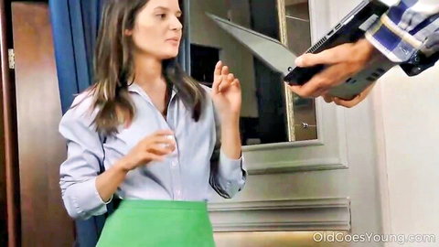 Slim brunette young woman in green skirt and blue blouse gestures to older man holding laptop