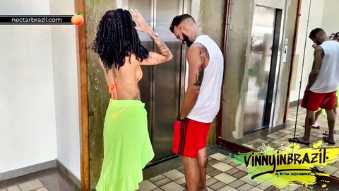 Curly-haired Brazilian beauty in orange bikini and green sarong with tattooed men behind the scenes - Vinny In Brazil