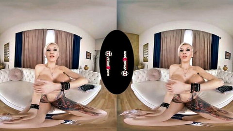 Blonde tattooed woman spreads shaved pussy wide on couch, pierced tits bare in VR