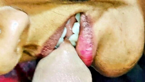 Close-up of brown-skinned woman sucking black cock with teeth and tongue