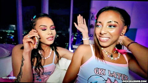 Ari Alectra and Zerella Skies, sexy ebony models smiling in colorful tops, teasing vibe