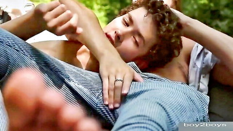 Curly-haired young man embraced intimately outdoors by partner