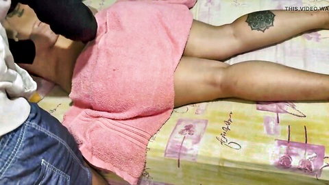 Sensual Indian woman in pink towel lies on bed as man caresses her face intimately