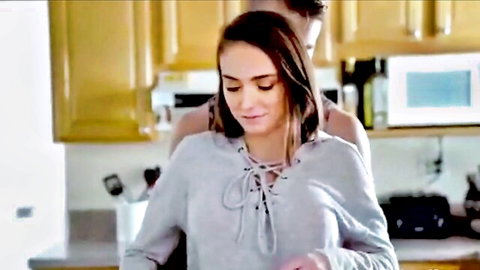 Brunette stepdaughter in gray hoodie hugged from behind by stepdad in kitchen taboo tease