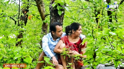 Indian couple passionately embracing with girlfriend on boyfriend's lap in lush forest outdoor romance
