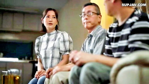 Japanese brunette stepmom in checkered blouse sits chatting with two clothed Asian men on couch