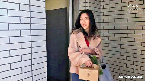 Japanese housewife smiling seductively holding box at door in coat