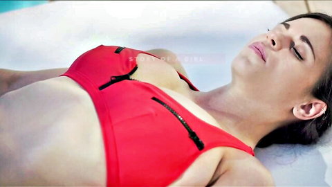 Tanned curvy brunette with huge natural tits in red zipper bikini lounging poolside