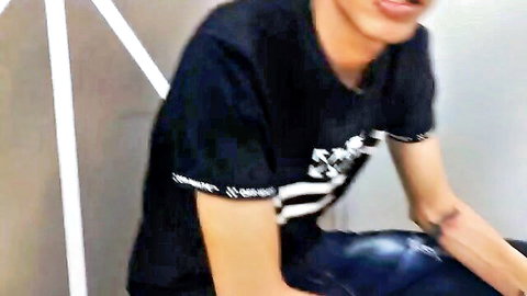 Young amateur teen guy in tight black Guess shirt and blue jeans sitting spread-legged on bed