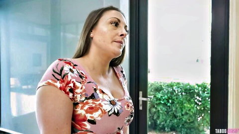 Curvy MILF with huge tits in low-cut pink floral dress teasing cleavage by glass door