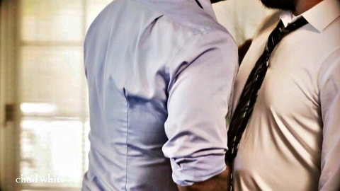 Two suited men embracing intimately from behind in office room
