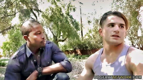 Muscular black bull in shirt stares intensely at ripped white stud in tank top outdoors in interracial cuckold setup