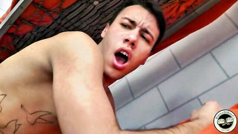 Tattooed muscular guy screaming in ecstasy gripping prison net in shower