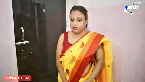 Desi hot bhabhi in yellow saree and red blouse standing seductively indoors