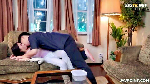 Reona Kirishima in passionate embrace with lover, clothed intimacy on couch
