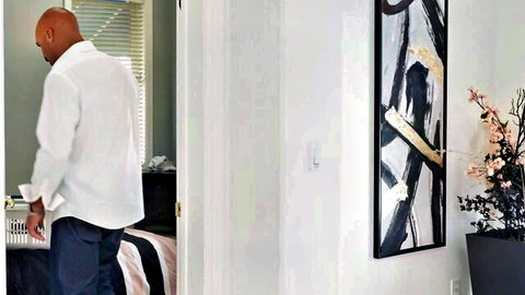 Bald black man in white shirt entering bedroom for private desires