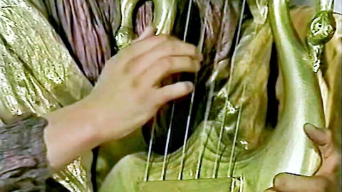 Jennifer Loca playing ornate lyre in golden costume from 1997 Italian film The Perverted Emperor
