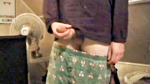 Amateur guy pulls down green patterned shorts exposing his erect cock solo.