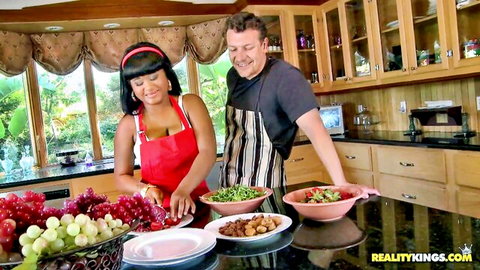 Ebony Stacey Monroe in red apron cooking with Jerry in kitchen