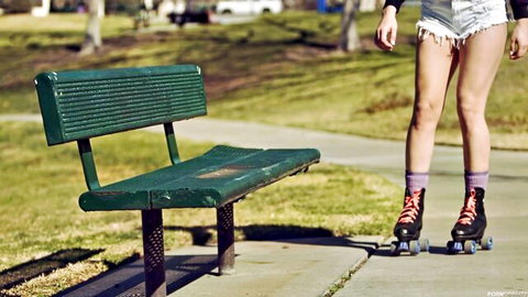 Blonde millennial in tiny shorts and roller skates poses outdoors
