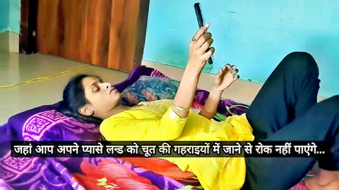 Indian amateur girl in yellow top and black pants lies on bed holding phone