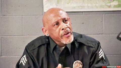 Bald black police officer in uniform gesturing and speaking in studio interview