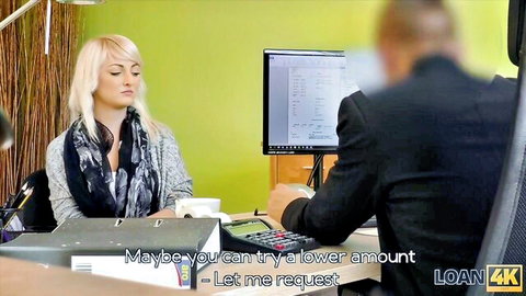 Blonde loan agent in gray sweater negotiates with suited man at office desk