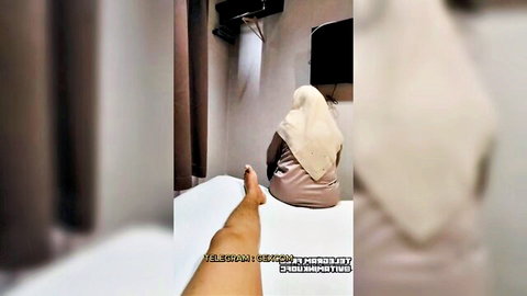 Malaysian hijabi MILF in pink top sits on hotel bed lifting foot teasing POV