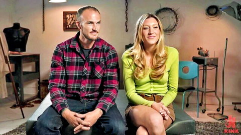 Blonde babe in tiny green skirt sits with bearded daddy on Kink BDSM couch