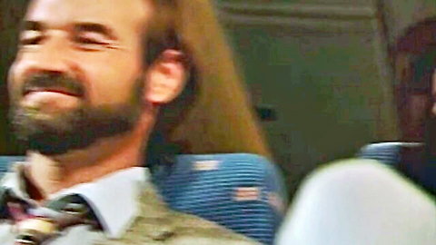 Bearded man in suit smiling on airplane seats, Anna Malle in Sky's The Limit