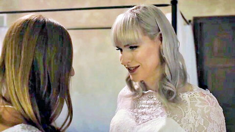 Platinum blonde bride in lace wedding dress intimately facing curvy brunette woman