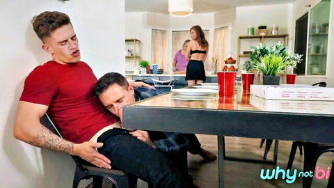 Muscular tattooed hunk slouched in chair gets bisexual handjob at kitchen table while sluts watch