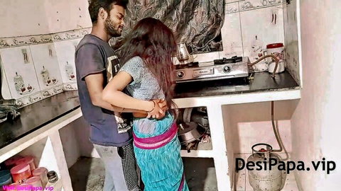Indian couple in traditional attire embracing intimately in kitchen