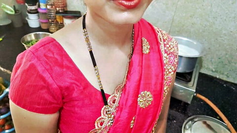 Sexy Indian housewife in red saree blouse smiling in kitchen with mangalsutra teasing cleavage