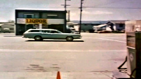 Vintage turquoise station wagon parked at rural liquor store in classic adult film