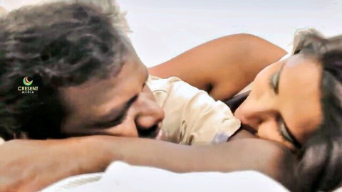 Passionate South Asian couple intimately kissing on bed in steamy embrace